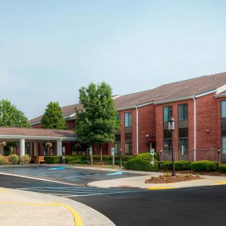 A brick hotel building with a landscaped entrance and driveway.