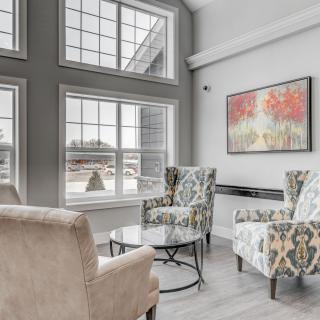 A modern living room with large windows, armchairs, and colorful artwork.