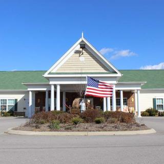 A building with a green roof and an American flag displayed at the entrance on a sunny day.