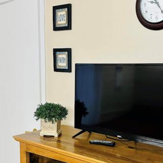 A cozy living room setup featuring a television on a wooden console, accompanied by decorative frames and a small plant.