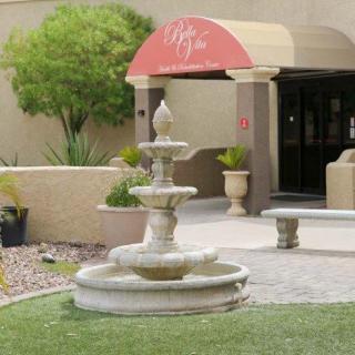 A two-tiered stone fountain in front of a building entrance with an awning.
