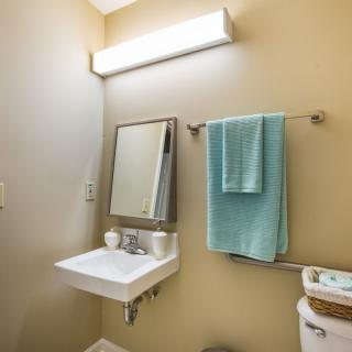 A clean and simple bathroom with a wall-mounted sink, mirror, and teal towels.