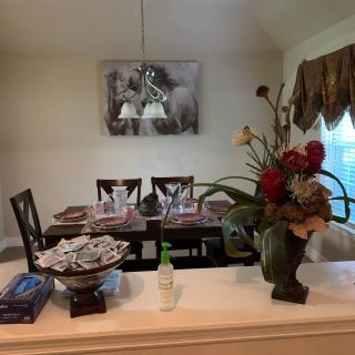 A well-decorated dining room with a table set for a meal, featuring a floral arrangement and artwork on the wall.