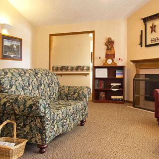 A cozy living room featuring a patterned sofa, fireplace, bookshelf, and decorative items.