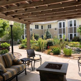 A cozy outdoor patio with a pergola, surrounded by lush gardens and comfortable seating.