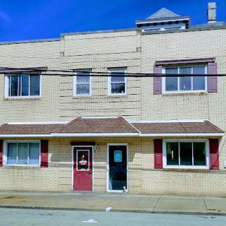 A charming two-story building with a unique architectural style, featuring multiple windows and a distinct red door.