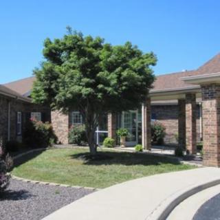 A brick house with a well-maintained lawn and a tree in the front yard.