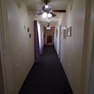 A long, carpeted hallway with ceiling fans and multiple doors.