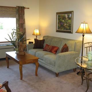 A cozy living room setting with a sofa, coffee table, and lamps.