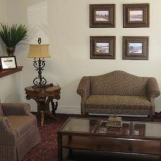 A cozy living room with a sofa, armchair, and coffee table, complemented by decorative artwork on the wall.