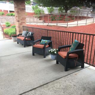 Outdoor patio area with cushioned chairs and a railing.