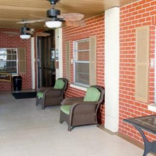 A cozy porch area with wicker chairs, brick walls, and ceiling fans.