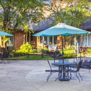 A peaceful outdoor patio with tables and umbrellas surrounded by greenery.