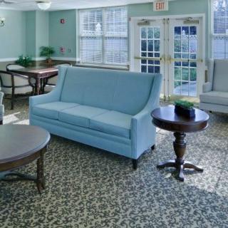 A cozy living room with a blue sofa, round tables, and large windows.