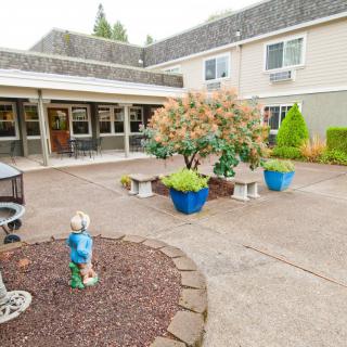 A peaceful courtyard with benches and potted plants in front of a building.