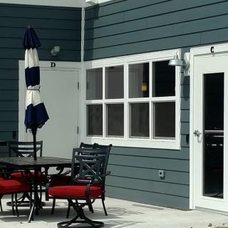 An outdoor patio with a table, chairs, and an umbrella next to the exterior of a house.