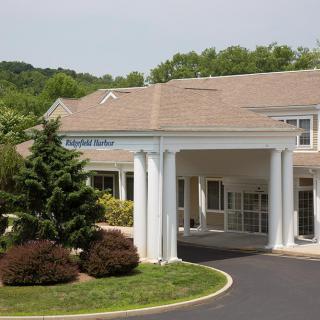 A building with a prominent entrance featuring white columns and surrounding greenery.