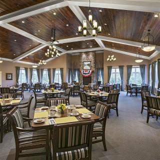An elegant dining room with neatly arranged tables and chandeliers.
