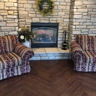 Cozy living room with a stone fireplace and striped chairs.