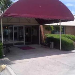 Entrance to a building with a red awning and surrounding greenery.