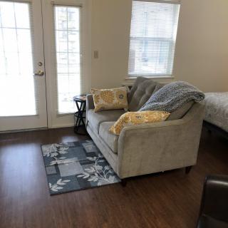 A cozy living space with a sofa, cushions, and decorative rug on a wooden floor.