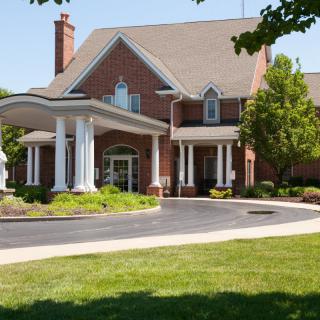 A large brick house with a welcoming porch and landscaped driveway.