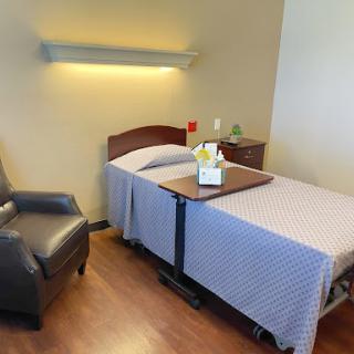 A serene hospital room featuring a bed, a chair, and a small table.