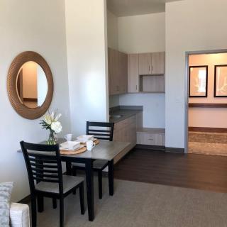 A minimalist dining area with a small table and two chairs, adjacent to a kitchenette.