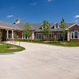 A large residential home with a spacious driveway and landscaped front yard under a clear blue sky.