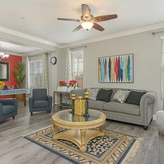A modern living room with stylish decor, featuring a grey sofa, a round coffee table, and colorful artwork on the wall.