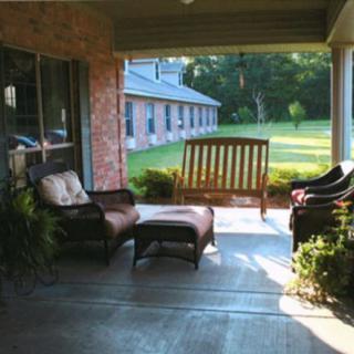 A cozy porch with seating and a swing overlooking a garden.