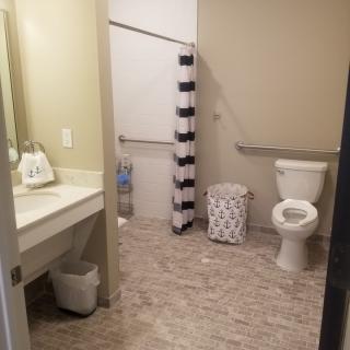 A clean and spacious bathroom with a toilet, sink, and shower area featuring a striped curtain.