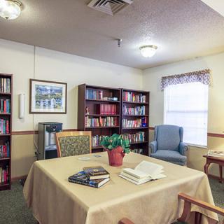 A cozy library room with bookshelves, a table, and chairs for reading.