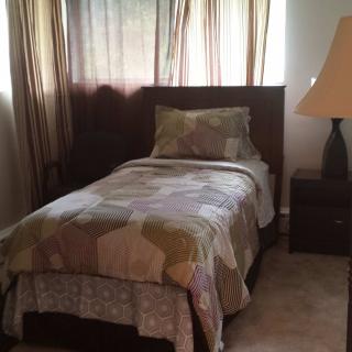 A cozy bedroom with a single bed, nightstand, and lamp.
