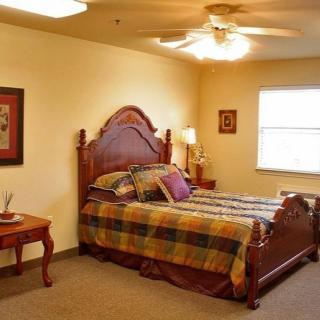 A cozy bedroom with a wooden bed frame and plaid bedding, featuring warm lighting.