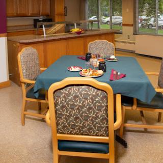 A cozy dining area featuring a table set with snacks and surrounded by comfortable chairs.