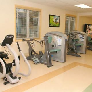 A clean, well-equipped gym room with various exercise machines.