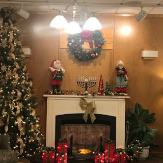 A cozy Christmas corner with decorations, a glowing fireplace, and festive elements.