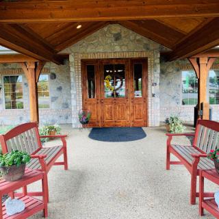 A welcoming entrance featuring wooden beams, stone accents, and red benches.