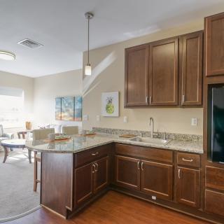 A modern kitchen with dark wood cabinets, granite countertops, and an open concept dining area.