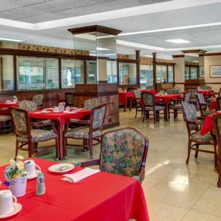 An empty restaurant dining area with red tablecloths on the tables.