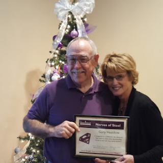 A proud moment as two individuals celebrate an achievement in front of a decorated holiday tree.