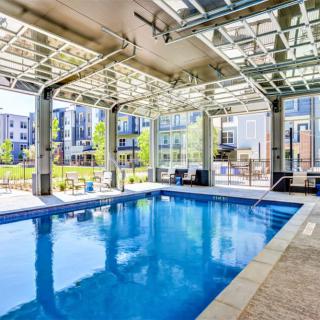 A modern indoor pool with glass walls offering a view of a residential complex.
