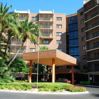 A mid-rise building with a welcoming entrance surrounded by palm trees and lush landscaping.