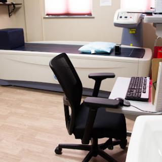 A view of a patient room in a medical facility featuring a hospital bed and a computer workstation.
