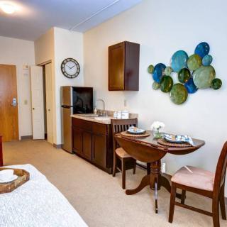 A cozy apartment interior featuring a kitchenette and a small dining area with wall art.