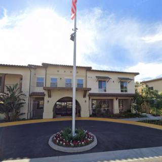 A sunny day view of a building with a flagpole at the entrance.