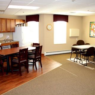A well-lit kitchen and dining area with tables and chairs.