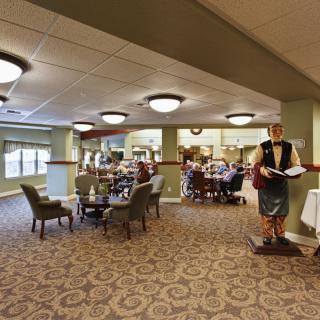 A spacious restaurant interior with a dining area featuring multiple tables and chairs, decorated with a waiter statue.