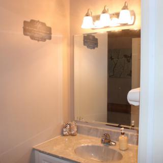 A bathroom vanity area with a sink, mirror, and overhead lighting.